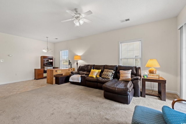 tiled living room featuring ceiling fan with notable chandelier