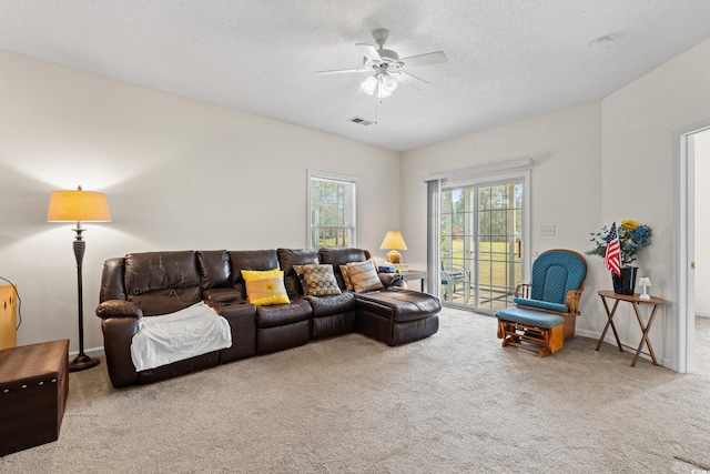 carpeted living room featuring ceiling fan and a textured ceiling