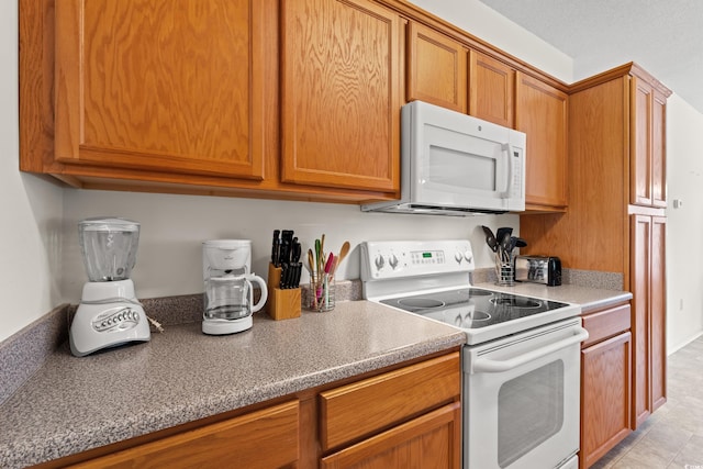 kitchen featuring light tile flooring and white appliances