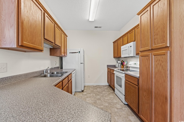 kitchen featuring white appliances, a textured ceiling, sink, and light tile floors