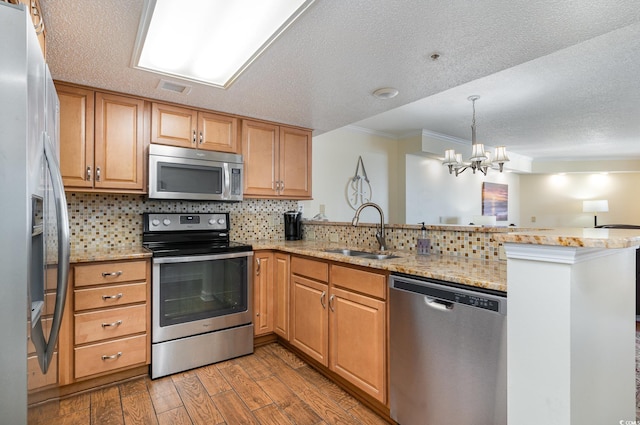 kitchen with kitchen peninsula, sink, light wood-type flooring, stainless steel appliances, and a chandelier