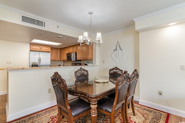 dining room with an inviting chandelier, a textured ceiling, crown molding, and light hardwood / wood-style flooring