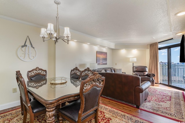 dining room featuring expansive windows, a textured ceiling, hardwood / wood-style floors, crown molding, and an inviting chandelier