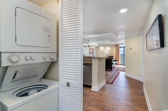 washroom featuring stacked washer and dryer, a textured ceiling, dark hardwood / wood-style floors, and a chandelier