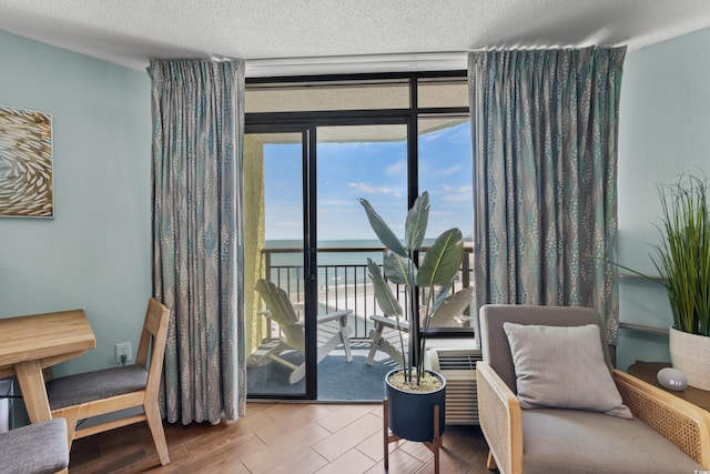 sitting room with a water view, a textured ceiling, and light hardwood / wood-style flooring