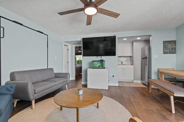 living room with ceiling fan, a textured ceiling, and hardwood / wood-style flooring