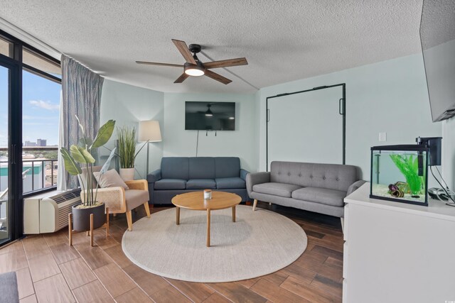 living room with a textured ceiling, floor to ceiling windows, ceiling fan, and hardwood / wood-style flooring