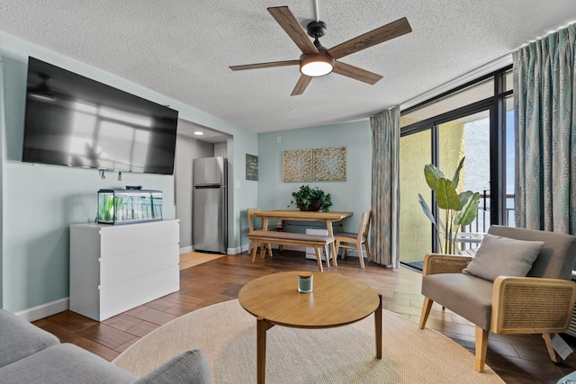 living room featuring ceiling fan, light hardwood / wood-style floors, and a textured ceiling