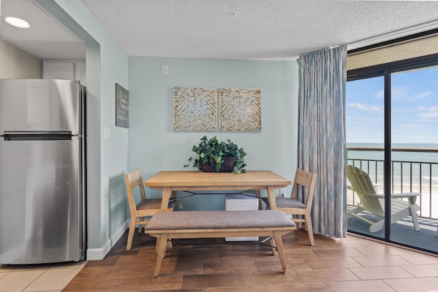 dining space with a water view and a textured ceiling