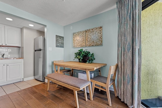 tiled dining area featuring a textured ceiling and sink