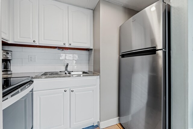 kitchen with white cabinetry, backsplash, stainless steel fridge, and sink