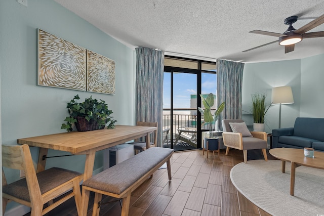 dining space featuring ceiling fan, a wall of windows, and a textured ceiling