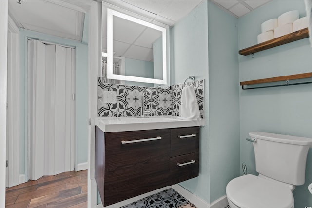 bathroom with vanity, a drop ceiling, backsplash, and toilet