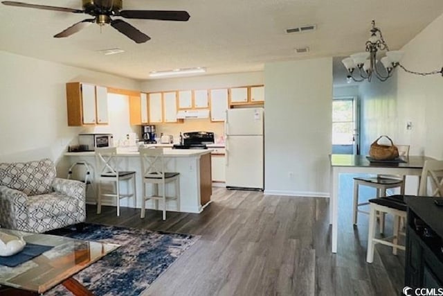 kitchen featuring extractor fan, dark hardwood / wood-style floors, a kitchen breakfast bar, white fridge, and stove