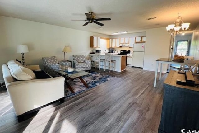 living room with dark wood-type flooring and ceiling fan with notable chandelier