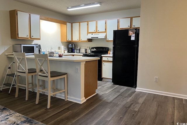 kitchen featuring black appliances, dark hardwood / wood-style flooring, a kitchen breakfast bar, kitchen peninsula, and white cabinets