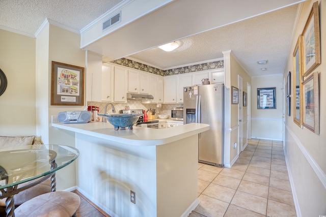 kitchen featuring stainless steel appliances, a textured ceiling, kitchen peninsula, tasteful backsplash, and white cabinetry