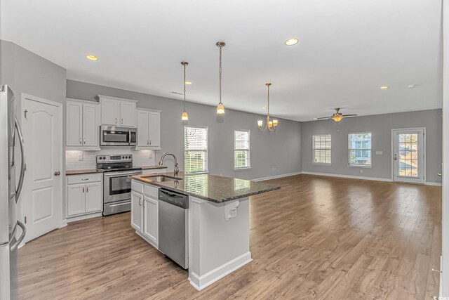 kitchen featuring white cabinets, stainless steel appliances, a center island with sink, and sink