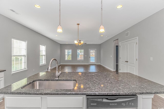 kitchen with dishwasher, dark stone counters, white cabinets, sink, and decorative light fixtures