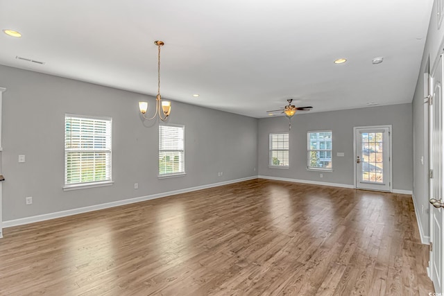 spare room with ceiling fan with notable chandelier and light hardwood / wood-style flooring