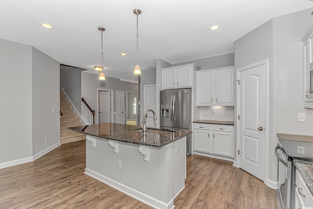 kitchen with a breakfast bar, white cabinetry, sink, and a kitchen island with sink