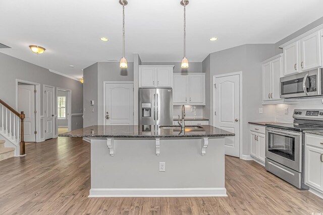 kitchen featuring backsplash, sink, appliances with stainless steel finishes, and an island with sink