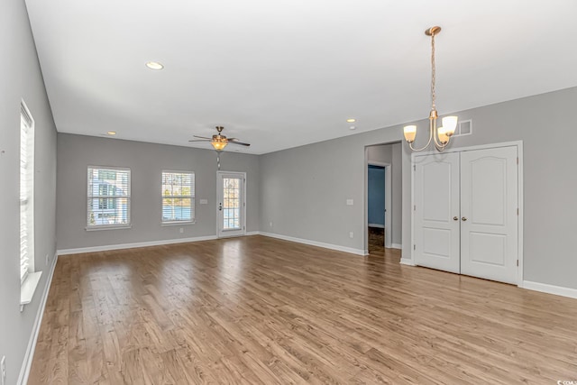 unfurnished living room featuring light hardwood / wood-style floors and ceiling fan with notable chandelier