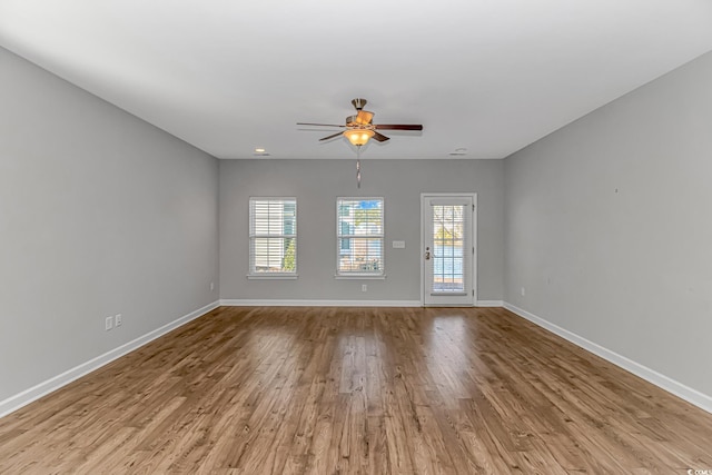 empty room with light hardwood / wood-style floors, a wealth of natural light, and ceiling fan