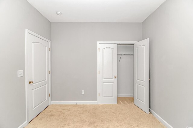 unfurnished bedroom featuring light carpet and a closet