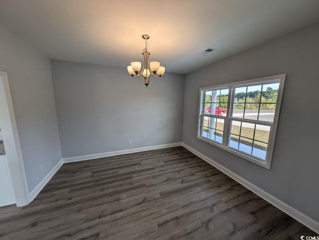 unfurnished room with visible vents, baseboards, a notable chandelier, and dark wood-style floors