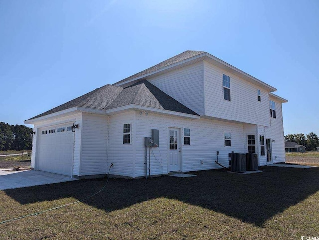 back of house featuring central AC, roof with shingles, a yard, a garage, and driveway