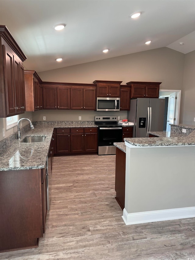 kitchen featuring appliances with stainless steel finishes, lofted ceiling, sink, and light wood-type flooring