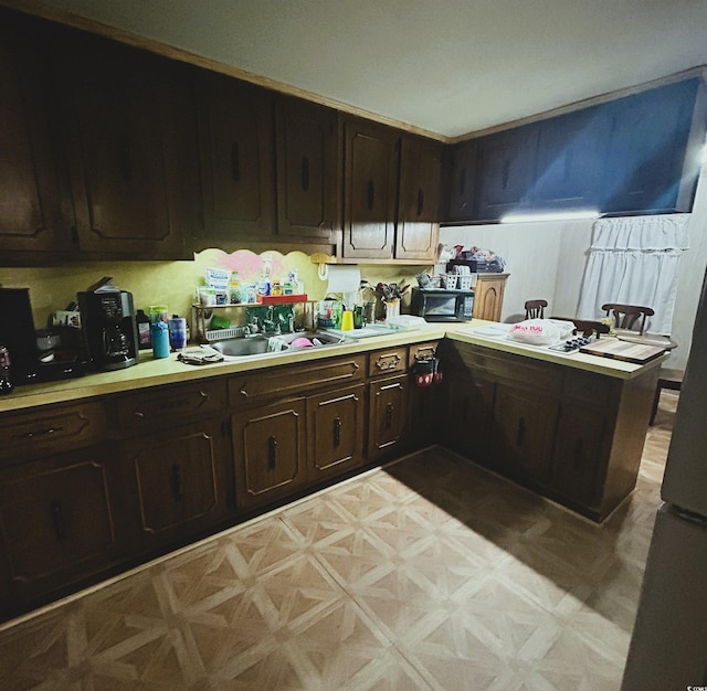 kitchen with parquet floors, sink, and dark brown cabinetry