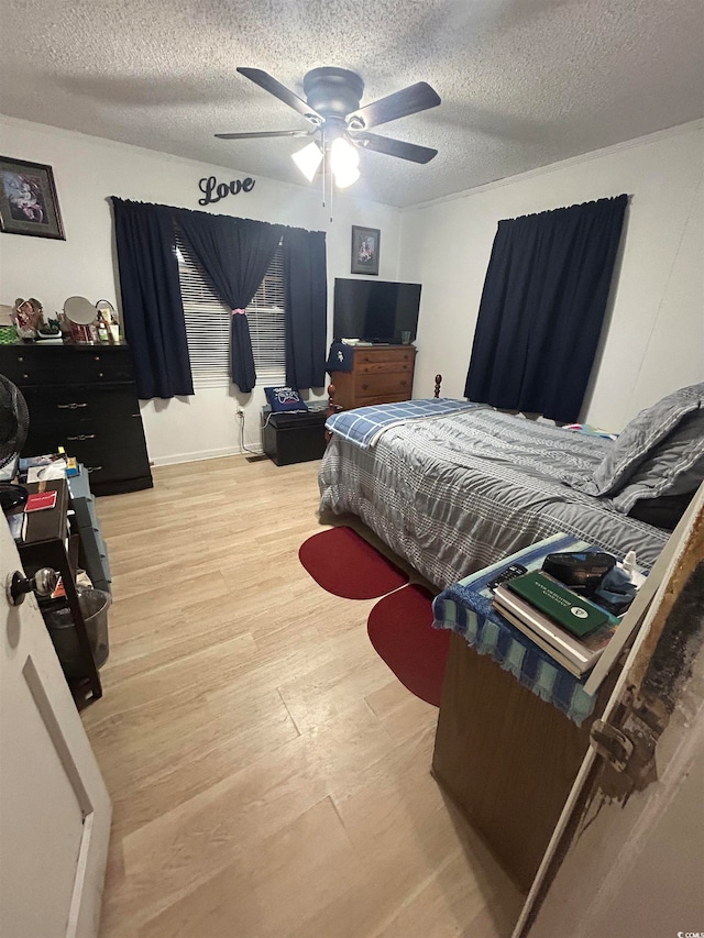 bedroom with a textured ceiling, ceiling fan, and light hardwood / wood-style flooring