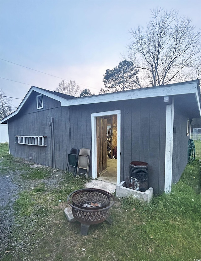 view of outdoor structure featuring an outdoor fire pit and a yard