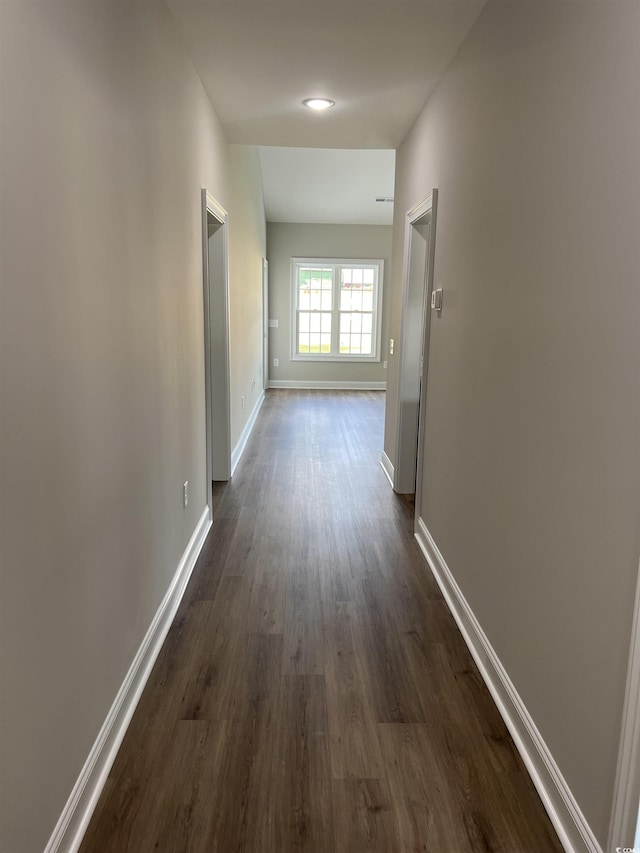 hallway featuring baseboards and dark wood-style flooring