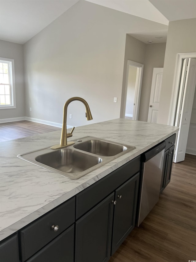 kitchen with dark wood-type flooring, a sink, stainless steel dishwasher, light countertops, and vaulted ceiling