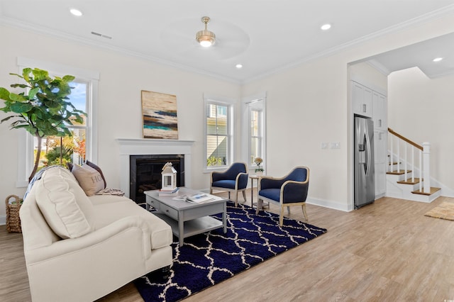 living room featuring ceiling fan, light wood-type flooring, and ornamental molding