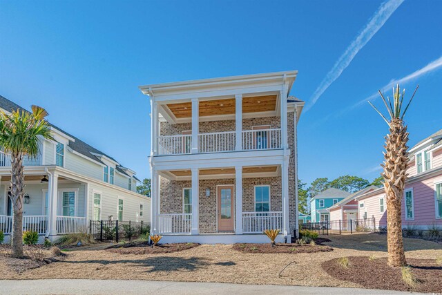 view of front facade featuring covered porch, a balcony, and a front lawn