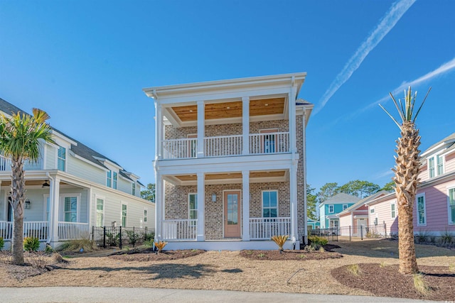 view of front of home featuring a balcony, fence, a porch, and brick siding