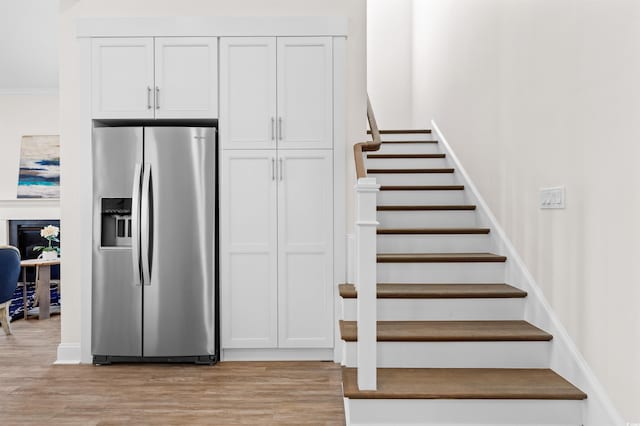 kitchen featuring crown molding, light wood finished floors, white cabinets, and stainless steel fridge with ice dispenser