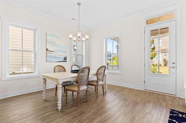 dining area featuring ornamental molding, a chandelier, baseboards, and wood finished floors