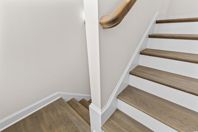 staircase featuring baseboards and wood finished floors