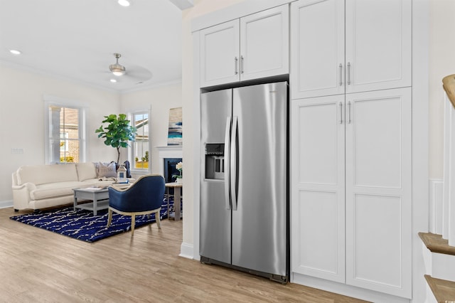 kitchen with white cabinets, stainless steel fridge with ice dispenser, light wood-style flooring, ornamental molding, and open floor plan