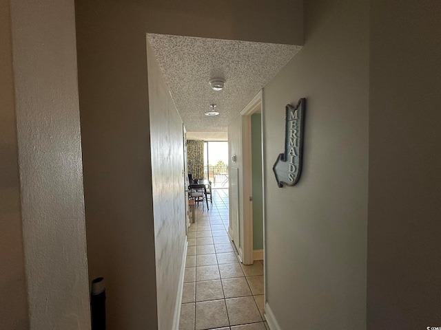 corridor featuring a textured ceiling and light tile floors