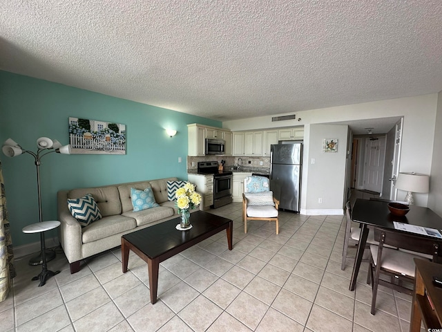 living room featuring light tile floors, sink, and a textured ceiling