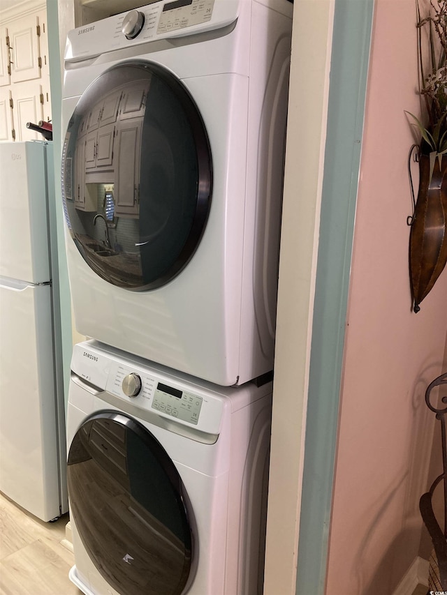 laundry room with stacked washer / drying machine and light wood-type flooring