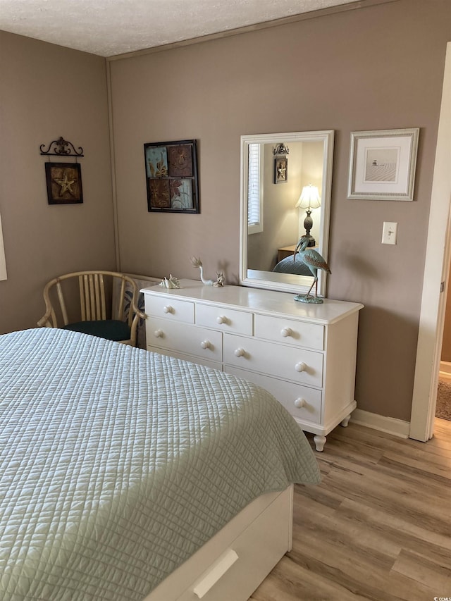 bedroom with light hardwood / wood-style floors and a textured ceiling