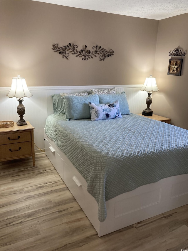 bedroom featuring light hardwood / wood-style floors and a textured ceiling