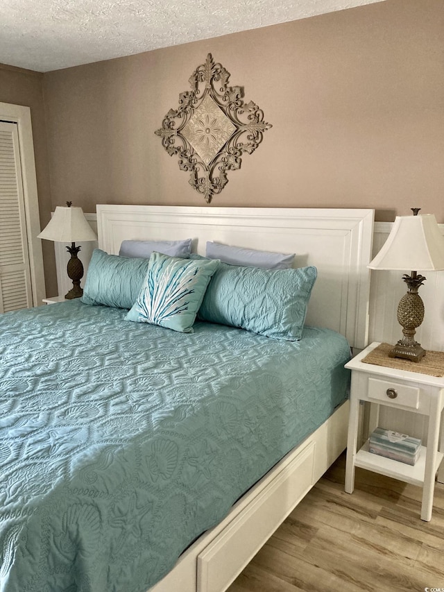 bedroom with a textured ceiling and hardwood / wood-style flooring